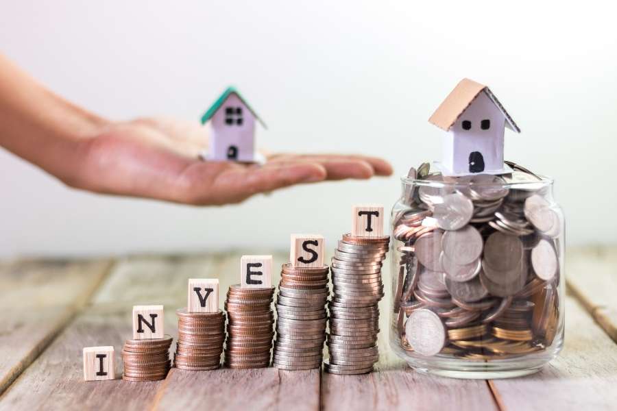 Des piles de pièces formant le mot "INVEST" avec une petite maison au sommet pour illustrer la rentabilité lors de la revente de votre bien immobilier.