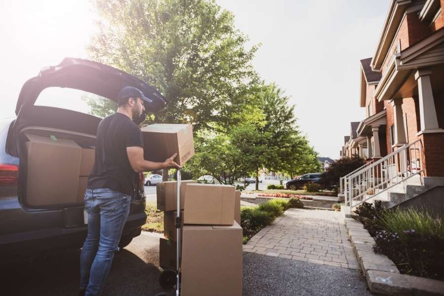 Un professionnel en tenue de travail utilise un diable pour charger des cartons, agissant comme un déménageur industriel efficace.