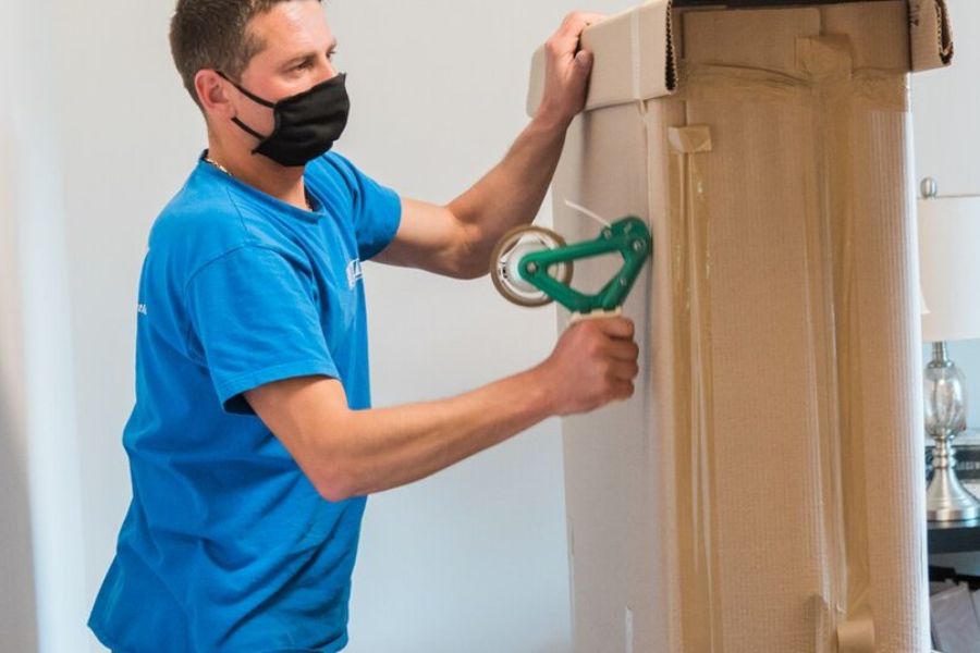 Un professionnel emballe un matelas dans du carton pour repérer les punaises de lit et empêcher leur propagation.
